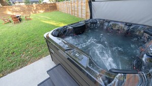 A hot tub with a control panel, surrounded by a wooden deck and a grassy yard. - East Austin Retreat w/ Hot Tub & Backyard (Austin)