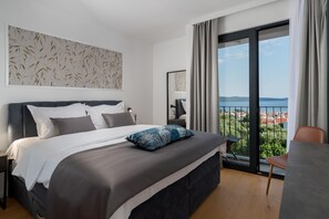 Ein modernes Hotelzimmer mit einem großen Bett, Blick auf die Stadt und einem Balkon mit Tisch und Stuhl.