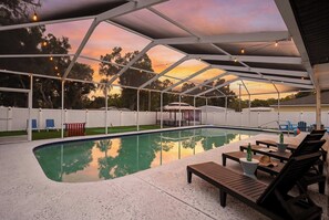 A covered outdoor swimming pool with lounge chairs and a gazebo. - 4BR Tampa retreat w/ private pool (Tampa)