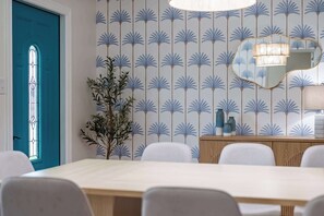 A dining area with a blue door, a wall with a palm tree pattern, a mirror, and a plant. - 4BR Tampa retreat w/ private pool (Tampa)