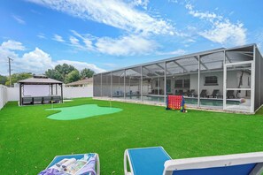 A covered outdoor area with artificial grass, a pool, and lounge chairs. - 4BR Tampa retreat w/ private pool (Tampa)