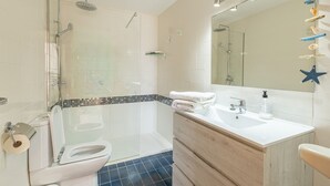 Une salle de bain moderne avec une douche en verre, un lavabo blanc avec un miroir et un meuble-lavabo en bois.