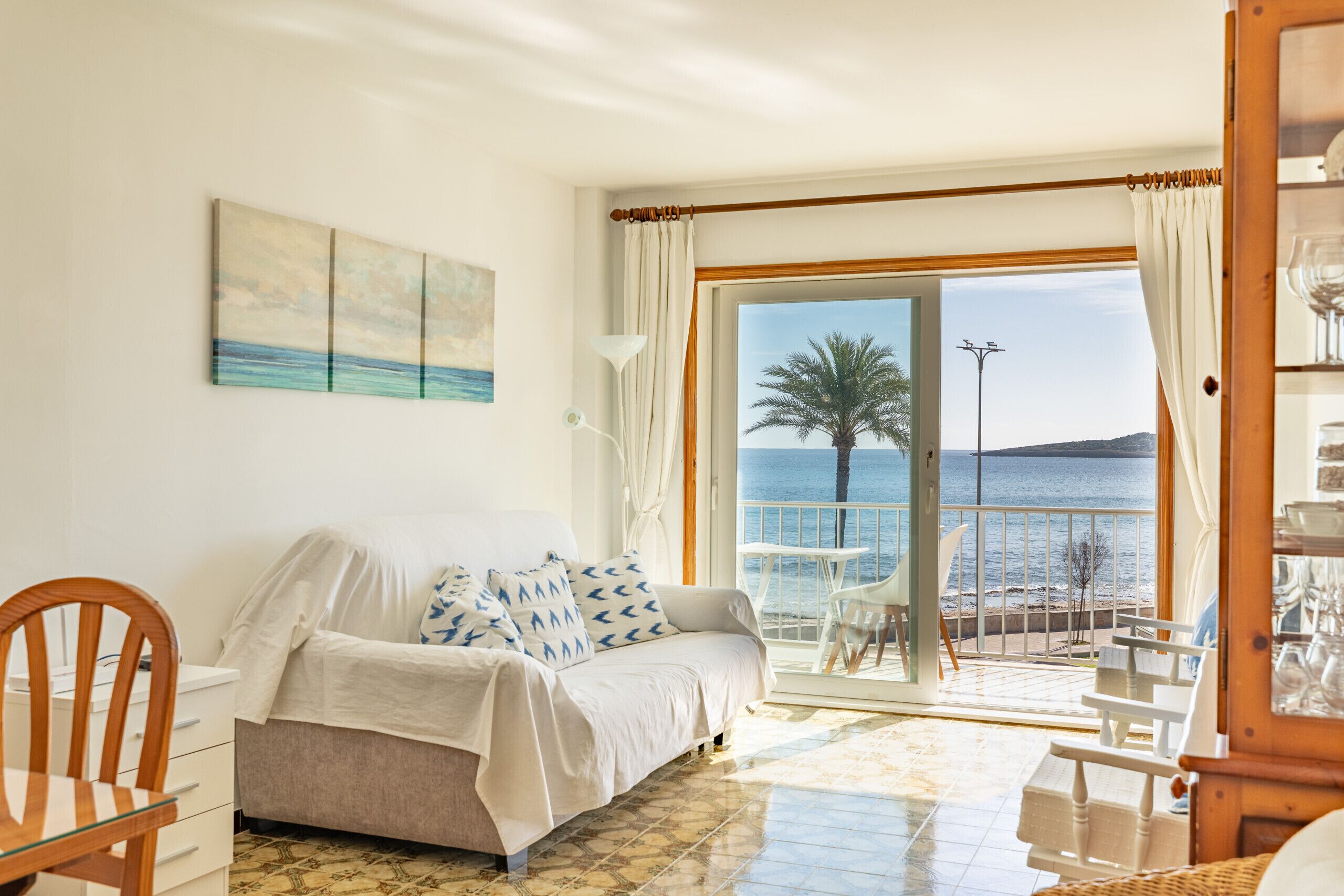 Une chambre avec un lit, une chaise, une table et une vue sur la mer.