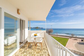 A balcony with a table and chairs, a view of the ocean, and a grassy area with a bench. - Skyline Cala Nau by Rentallorca (Cala Millor)