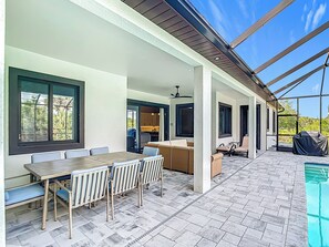 A covered patio with a pool, outdoor seating, and a kitchen area.