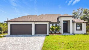 A modern two-story house with a garage, a small porch, and a well-maintained lawn.