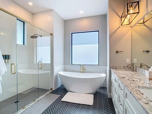A modern bathroom with a freestanding bathtub, a glass-enclosed shower, and a large mirror.