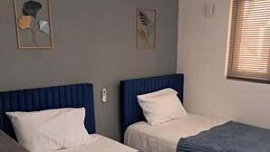Una habitación con dos camas, un escritorio y aire acondicionado.