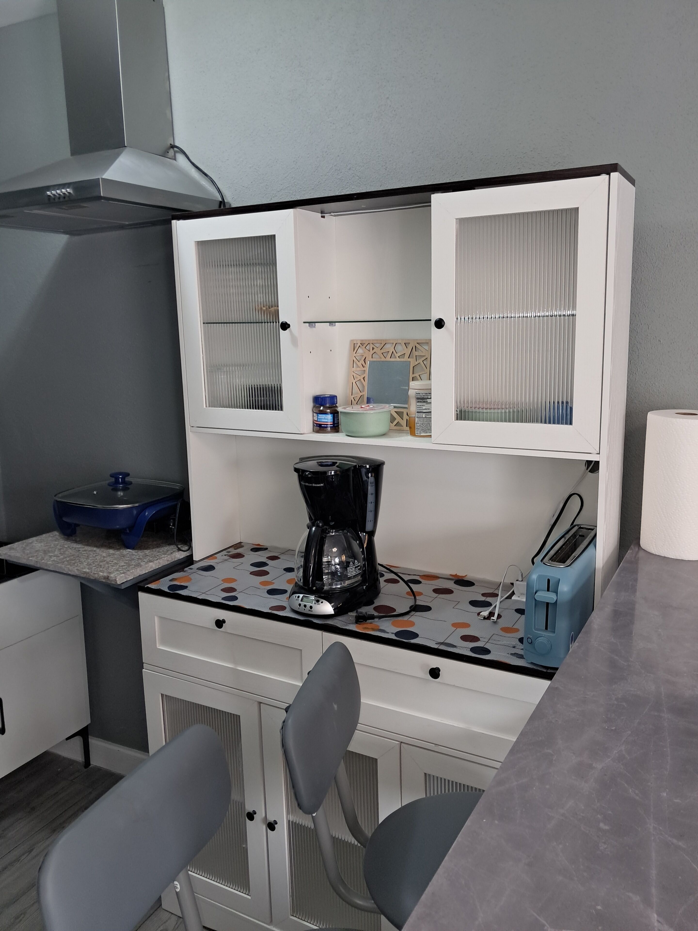 A kitchenette with a coffee maker, toaster, and cabinets.