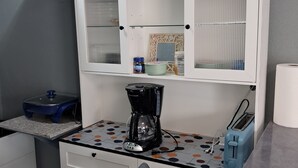 Una kitchenette equipada con cafetera, tostadora y armarios.
