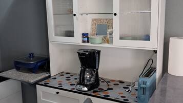 A kitchenette with a coffee maker, toaster, and cabinets.