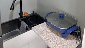 Una cocina compacta con un lavamanos, una estufa y una encimera.