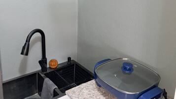 A compact kitchen with a sink, a stove, and a countertop.
