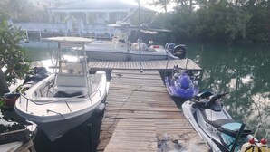 Un muelle con barcos, un jet ski y una embarcación motorizada.