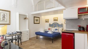Ein gemütlicher Raum mit Bett, einer kleinen Küchenzeile, einer Essecke mit Tisch und Stühlen sowie einem Dachfenster.