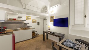 Eine kompakte Küche mit Essbereich, einem eingebauten Backofen und einem kleinen Tisch mit Lampe.