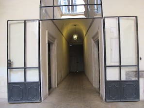 A corridor with a herringbone floor leading to a door with a glass panel. - Banchi Fontana - Castel Sant'Angelo (Rome)