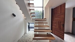 A modern interior with a wooden staircase, white walls, and a large wooden door. - Spectacular country house, in the coffee region, 5 minutes from the coffee park. (Armenia)