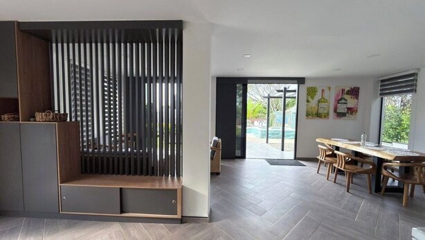 A modern interior with a wooden bench, a dining area with chairs, and a view through a glass door. - Spectacular country house, in the coffee region, 5 minutes from the coffee park. (Armenia)