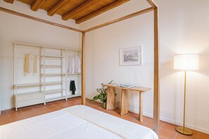 Makuuhuoneessa on sänky, vaatekaappi, yöpöytä lampun kanssa ja seinällä oleva kehystetty kuva.