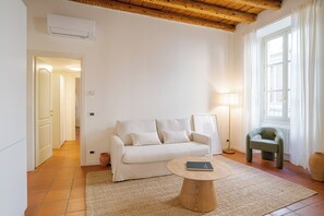 A living room with a sofa, a coffee table, a lamp, and a window with curtains. - Como Center Apartment Castrum, Como, Italy (Como)