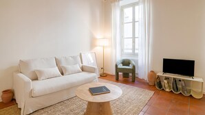 Een woonkamer met een bank, een salontafel, een televisie en een lamp.