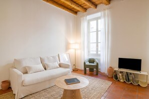 A living room with a sofa, a coffee table, a television, and a lamp. - Como Center Apartment Castrum, Como, Italy (Como)
