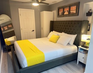 Een slaapkamer met een bed, nachtkastje en een plafondventilator.