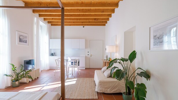 Un intérieur moderne avec un plafond en bois, un lit, un canapé, un coin repas et une cuisine.