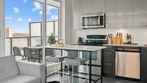 Una cocina moderna con un ventanal grande, microondas, estufa y lavavajillas.