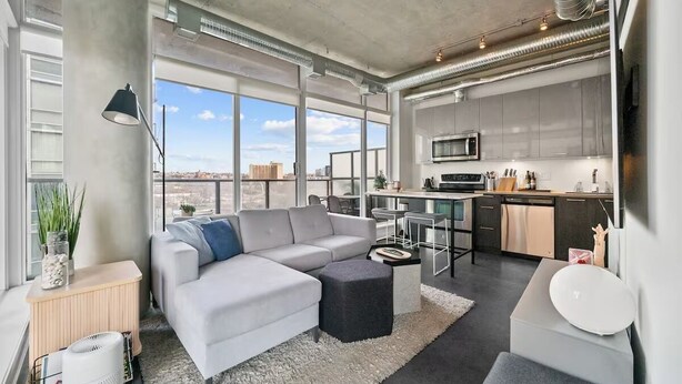 Un apartamento moderno con zona de estar, kitchenette y grandes ventanales.