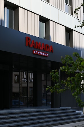 Un edificio con un cartel que dice 'RAMADA BY WYNDHAM' sobre la entrada.