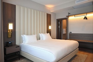 Una habitación de hotel con una cama grande, lámparas de noche, una mesita de noche, un espejo y un armario.