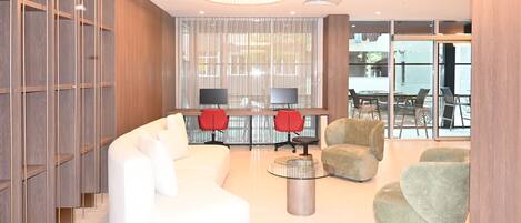 A modern interior with a white sofa, red chairs, a glass coffee table, and a large window with curtains.