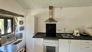 Una cocina con encimera negra, armarios blancos, un lavamanos de acero inoxidable y un horno empotrado.