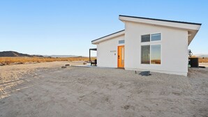 A modern, single-story building with a flat roof, a door with a number, and a window. - Luxury Desert Retreat on 5 Acres, Hot Tub, BBQ & Stargazing (Joshua Tree)