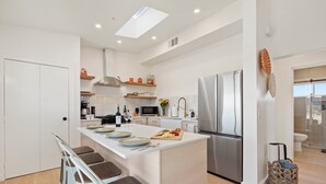 A modern kitchen with a central island, stainless steel appliances, and a breakfast bar. - Luxury Desert Retreat on 5 Acres, Hot Tub, BBQ & Stargazing (Joshua Tree)