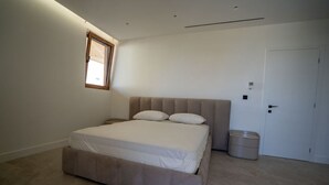 Une chambre à coucher avec un lit, une fenêtre, une porte et une poubelle.