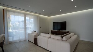 Un salon moderne avec un canapé, un téléviseur et une porte-fenêtre coulissante.
