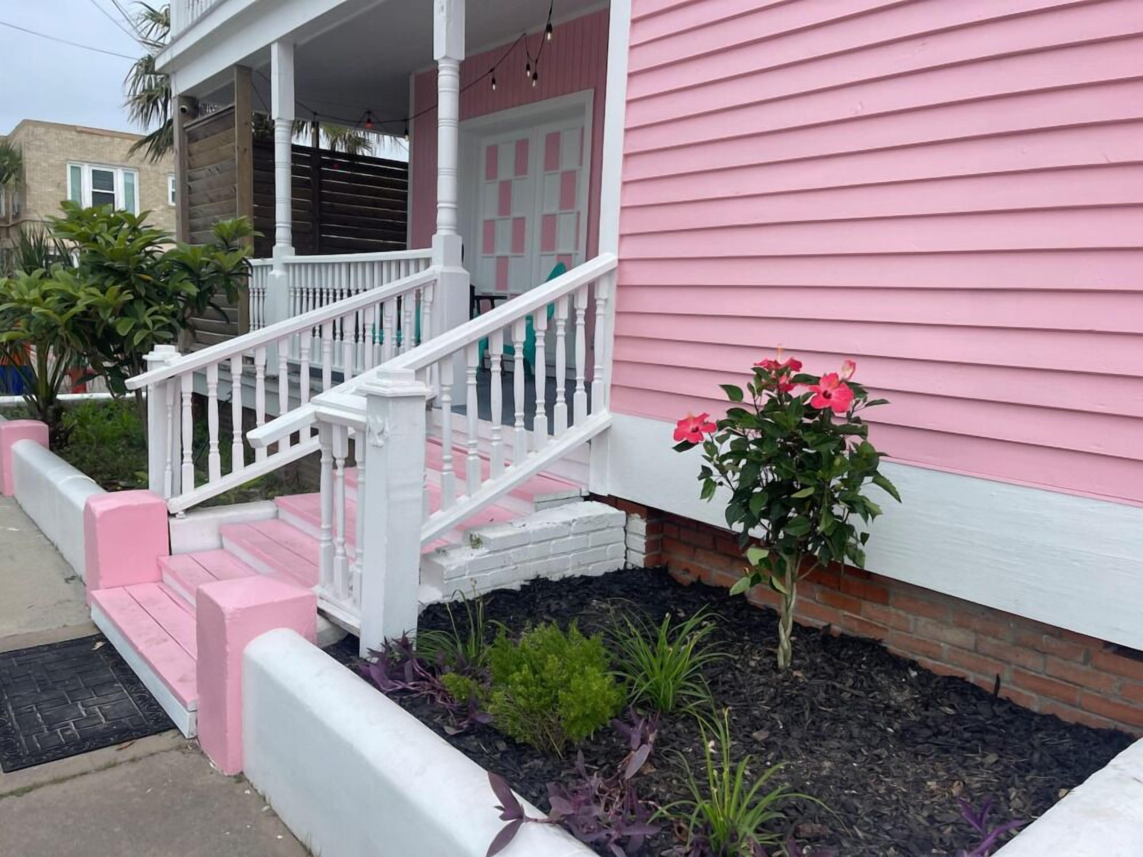 A pink house with a white porch and steps.