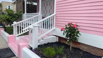 A pink house with a white porch and steps.