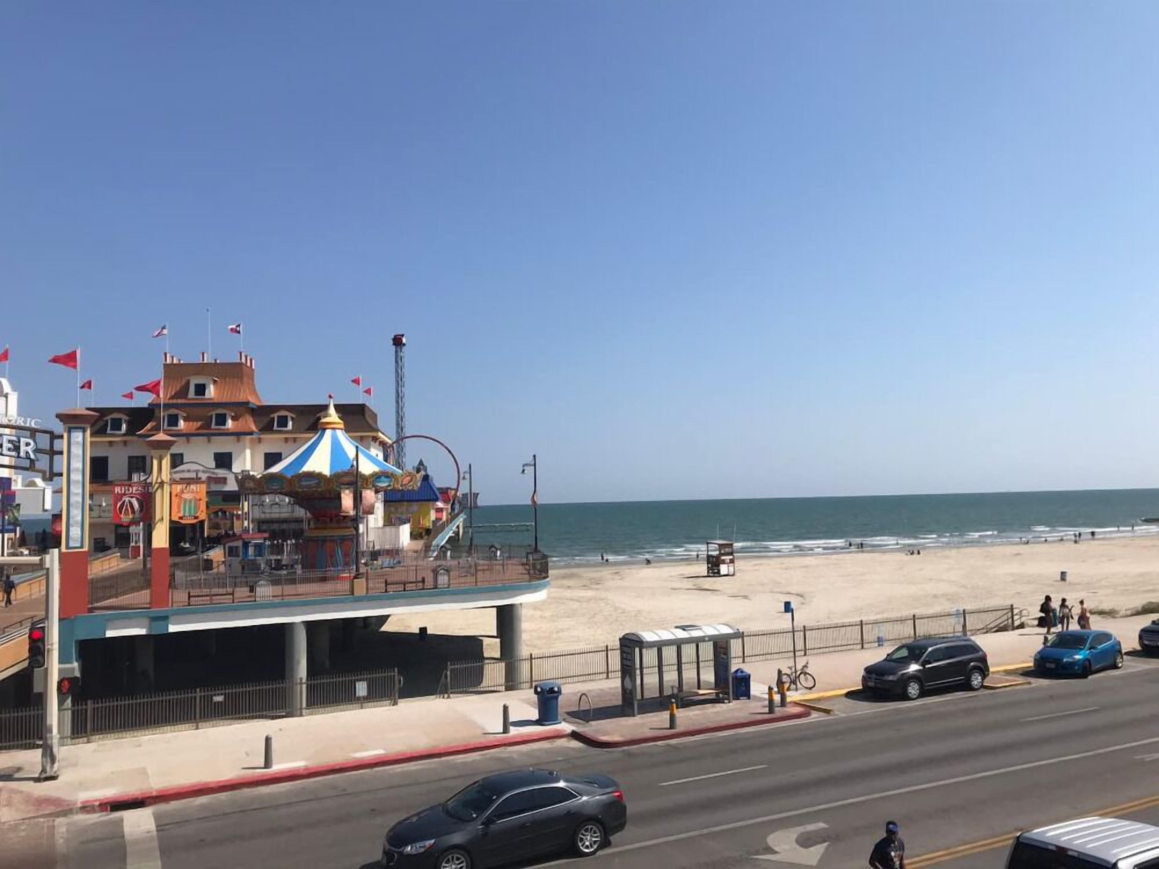 A coastal road with a beach, a carousel, and a building with a sign that reads 'RIDE'.