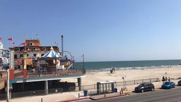 A coastal road with a beach, a carousel, and a building with a sign that reads 'RIDE'.