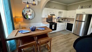 Een keuken met witte kastjes, een houten eettafel en een roestvrijstalen koelkast.