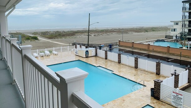 Ein Poolbereich mit Blick auf den Strand, eine Rettungswache und ein Gebäude mit einem Balkon.