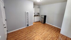 Una cocina con armarios blancos, un refrigerador y suelo de madera.