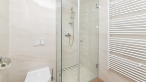 A modern bathroom with a glass-enclosed shower, a white bathtub, and a towel rack. - Altiora Prestige Residence 201 (Gradac)