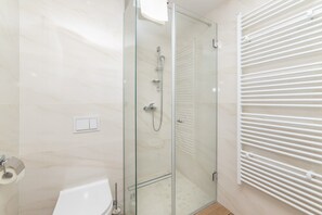 A modern bathroom with a glass-enclosed shower, a white bathtub, and a towel rack. - Altiora Prestige Residence 201 (Gradac)