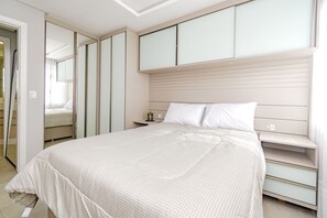 Ein Schlafzimmer mit einem Bett, einem Nachttisch, einem Kleiderschrank und einem Spiegel.