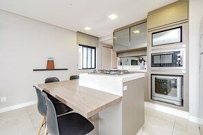 Eine moderne Küche mit Kochinsel, Einbauofen und Fenster.